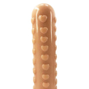 Primo piano dettaglio dildo color carne con rilievi a cuore verticali e finitura lucida