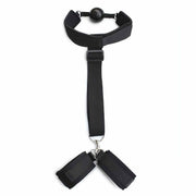 Accessorio BDSM nero ball-gag con polsiere collegate su sfondo bianco
