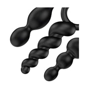 Dettaglio ravvicinato di tre plug anali neri in silicone morbido Satisfyer, forme a doppia sfera e spirale con anelli di ritenuta