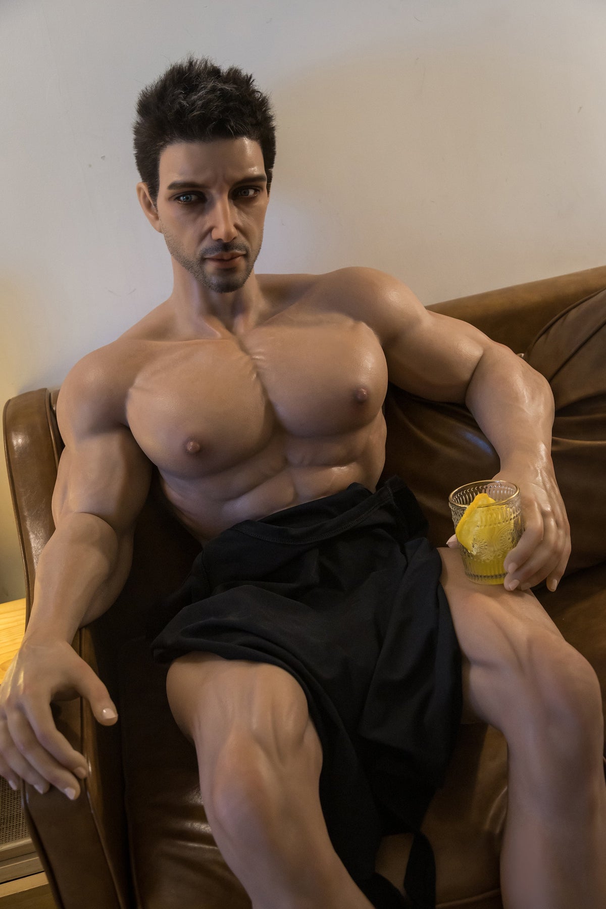 Manichino maschio Real Doll seduto su divano con bicchiere di vetro