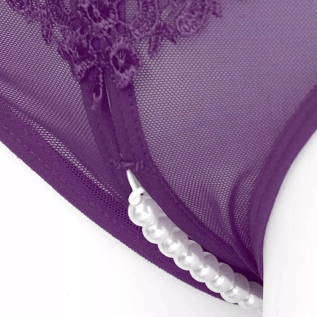 Dettaglio cuciture e perline bianche su perizoma viola in rete