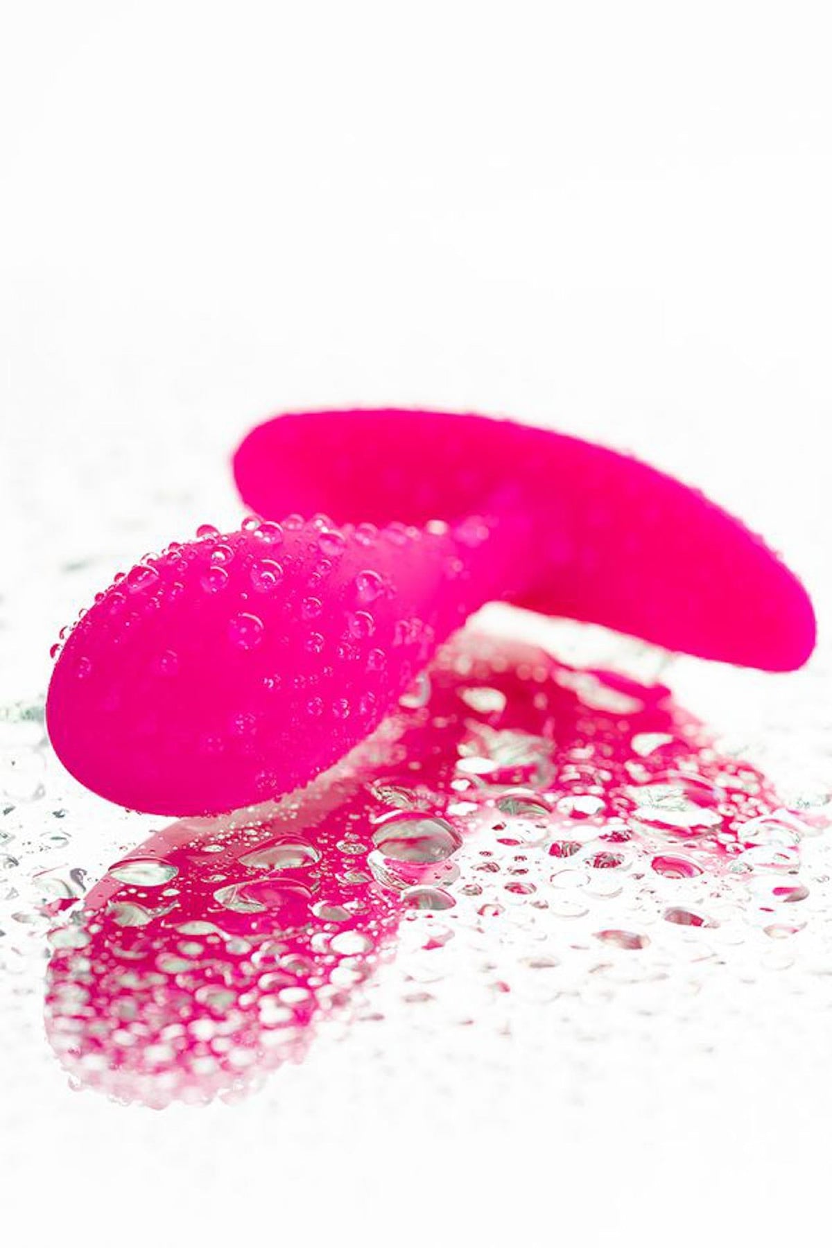 Plug anale rosa acceso in silicone lucido con gocce d'acqua
