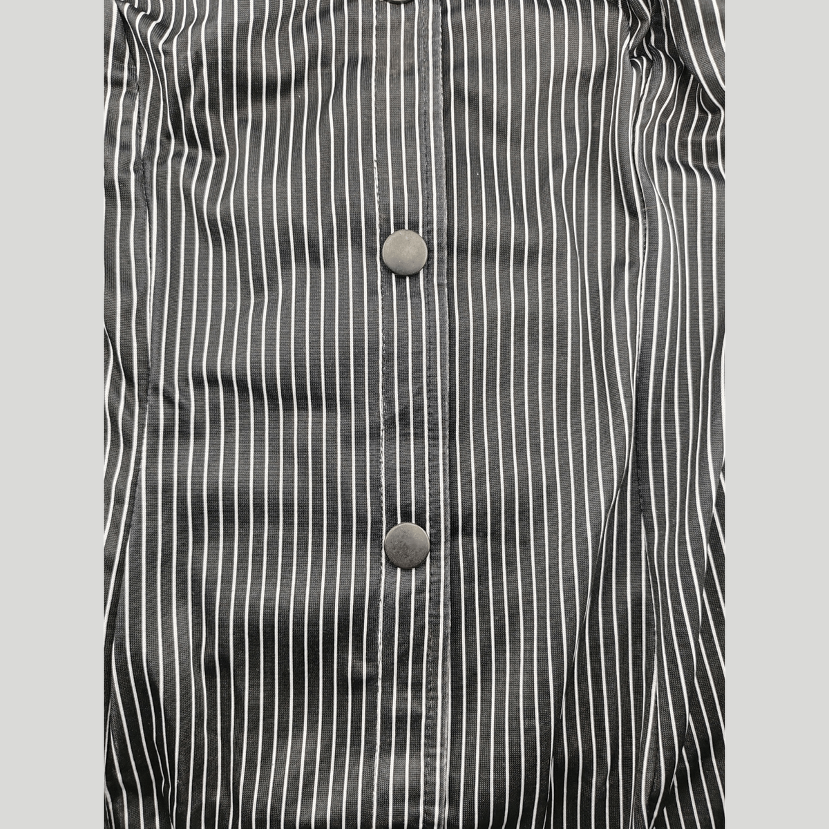 Dettaglio camicia a righe verticali nere e bianche con bottoni scuri per roleplay