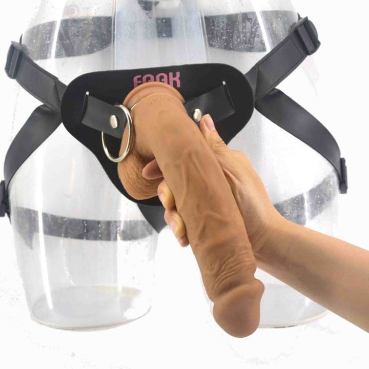 Strap-on color carne tenuto in mano con supporto nero